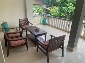 A balcony with a table and chairs, potted plants, and a view of greenery. - Kaya Hotel (Siem Reap)