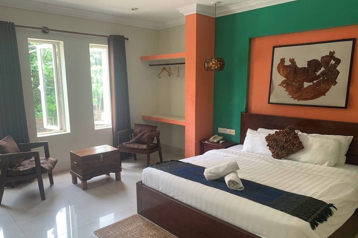 A hotel room with a bed, a desk, a chair, and a window.