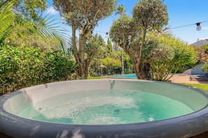 Une piscine entourée d’une végétation luxuriante et d’arbres.