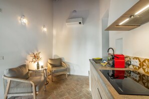 Un espace de vie compact comprenant un coin cuisine, un coin repas avec deux chaises, une petite table et un vase décoratif.
