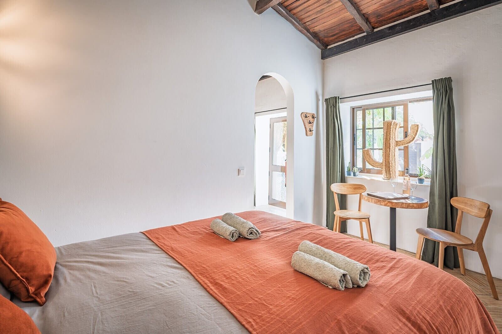 Une chambre d’hôtel avec un lit, une table et des chaises, et une fenêtre avec des rideaux.