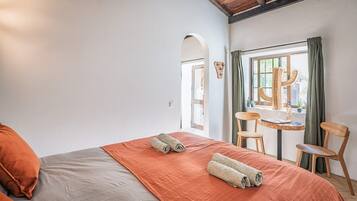 Une chambre d’hôtel avec un lit, une table et des chaises, et une fenêtre avec des rideaux.