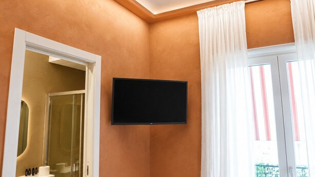 Un baño con televisión instalada, un lavamanos y una zona de ducha.