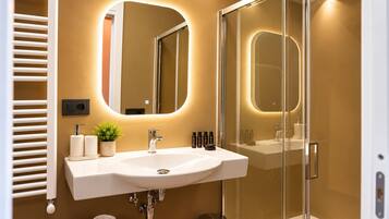 A modern bathroom with a white sink, a large mirror, and a glass shower enclosure.
