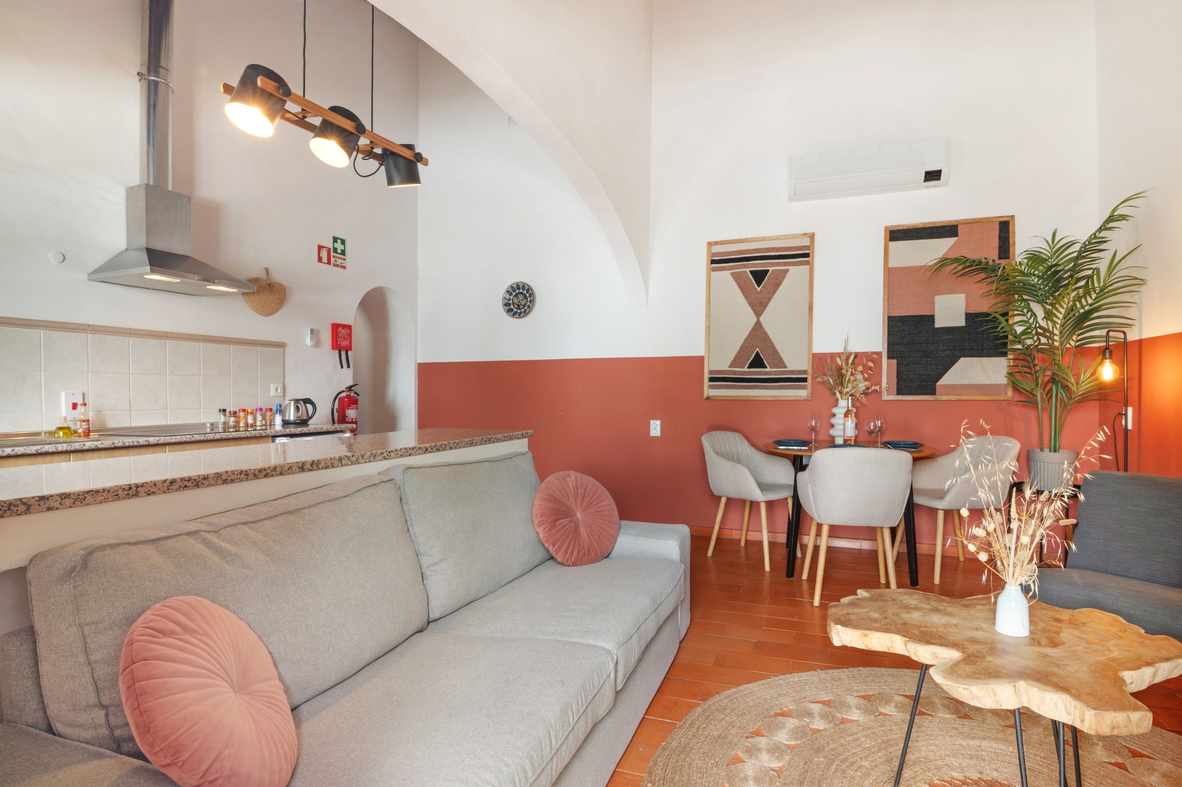 Una sala de estar moderna con un sofá, un comedor con una mesa y sillas, y una cocina con estufa y armarios.
