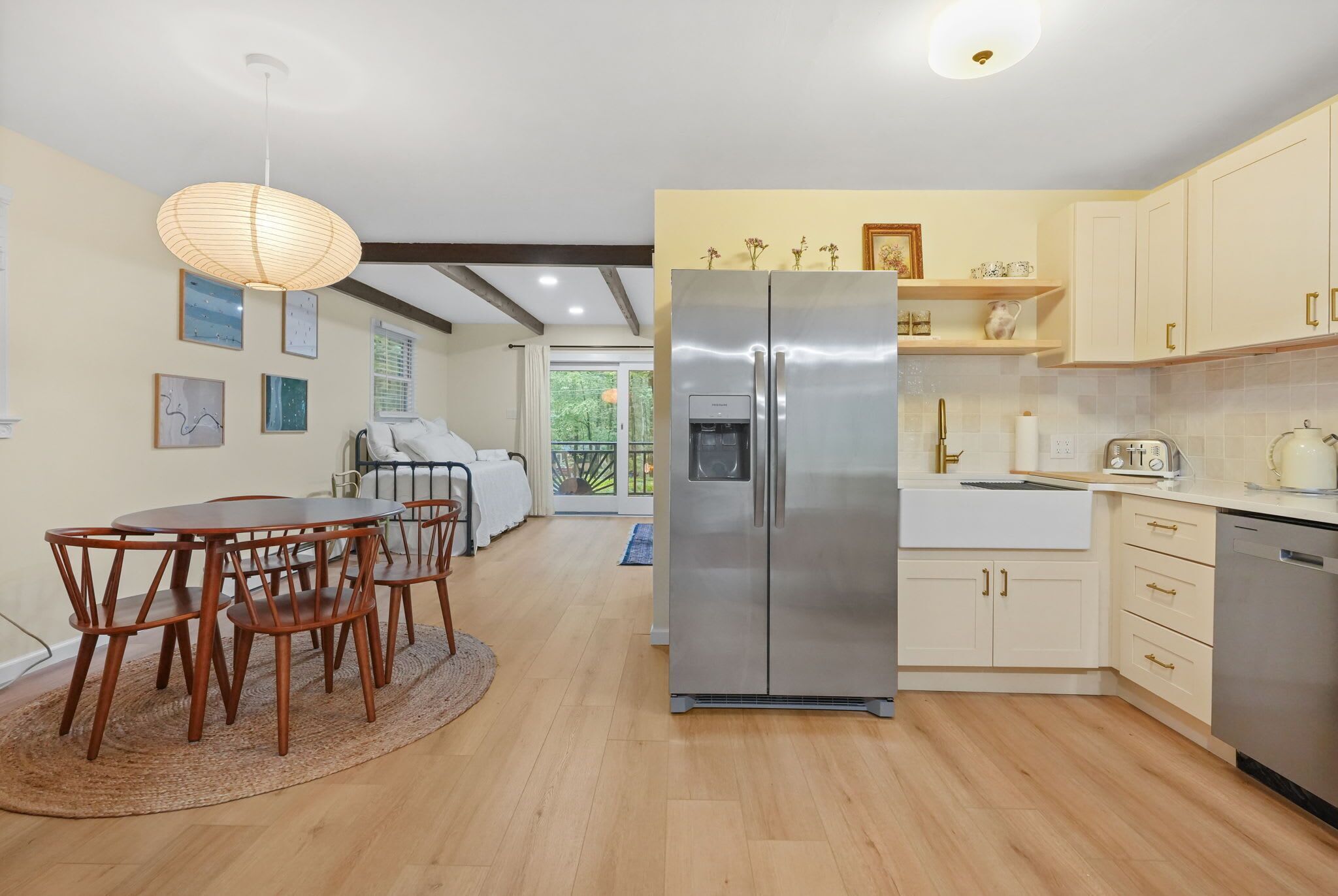 A modern kitchen with a stainless steel refrigerator, wooden dining table, and chairs.