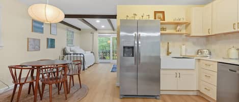 A modern kitchen with a stainless steel refrigerator, wooden dining table, and chairs.