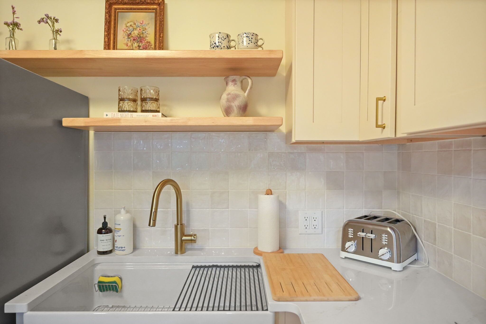 A kitchen with a sink, a toaster, and a cutting board on the countertop.