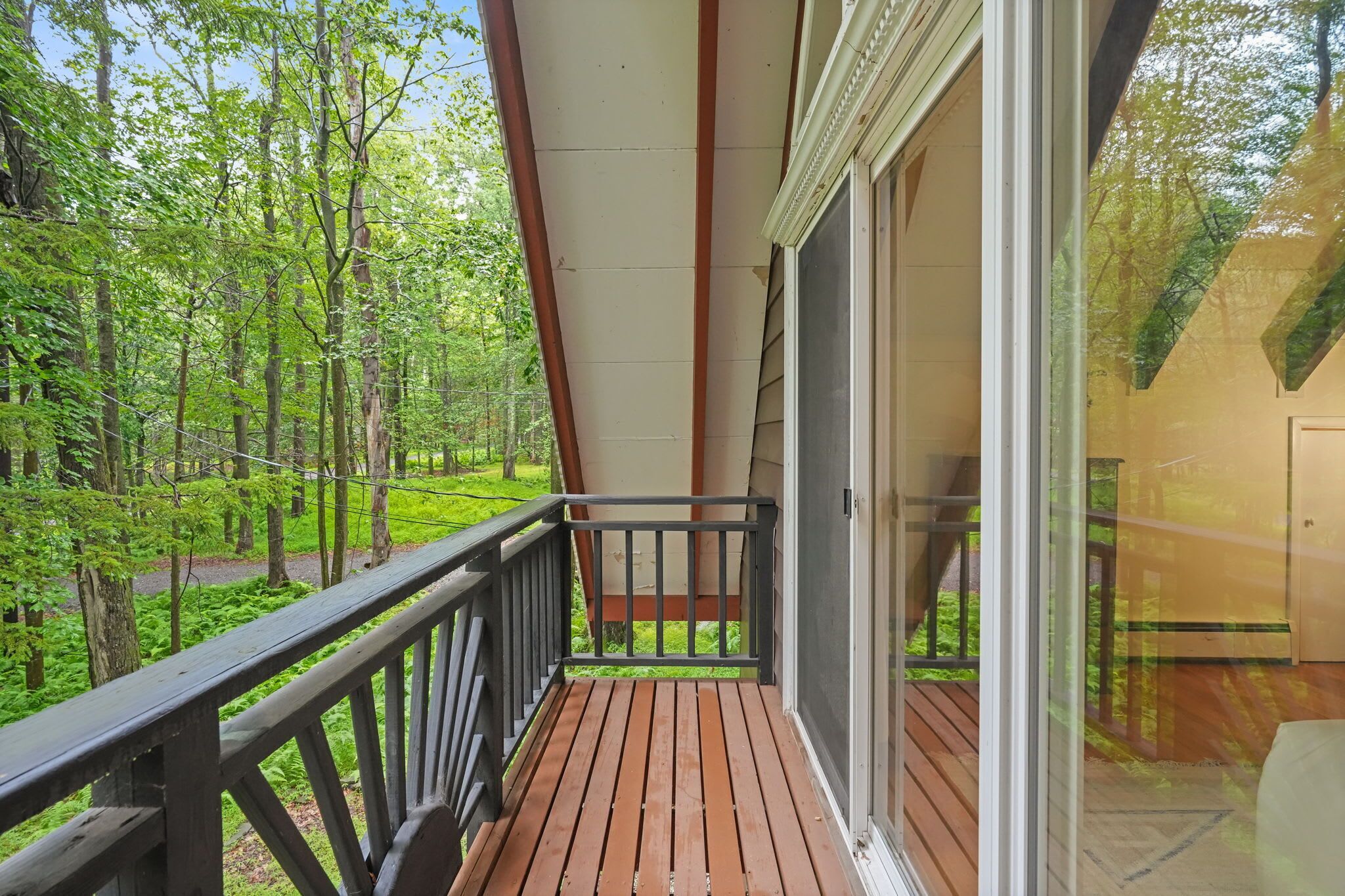 A wooden deck with a railing, overlooking a forested area.