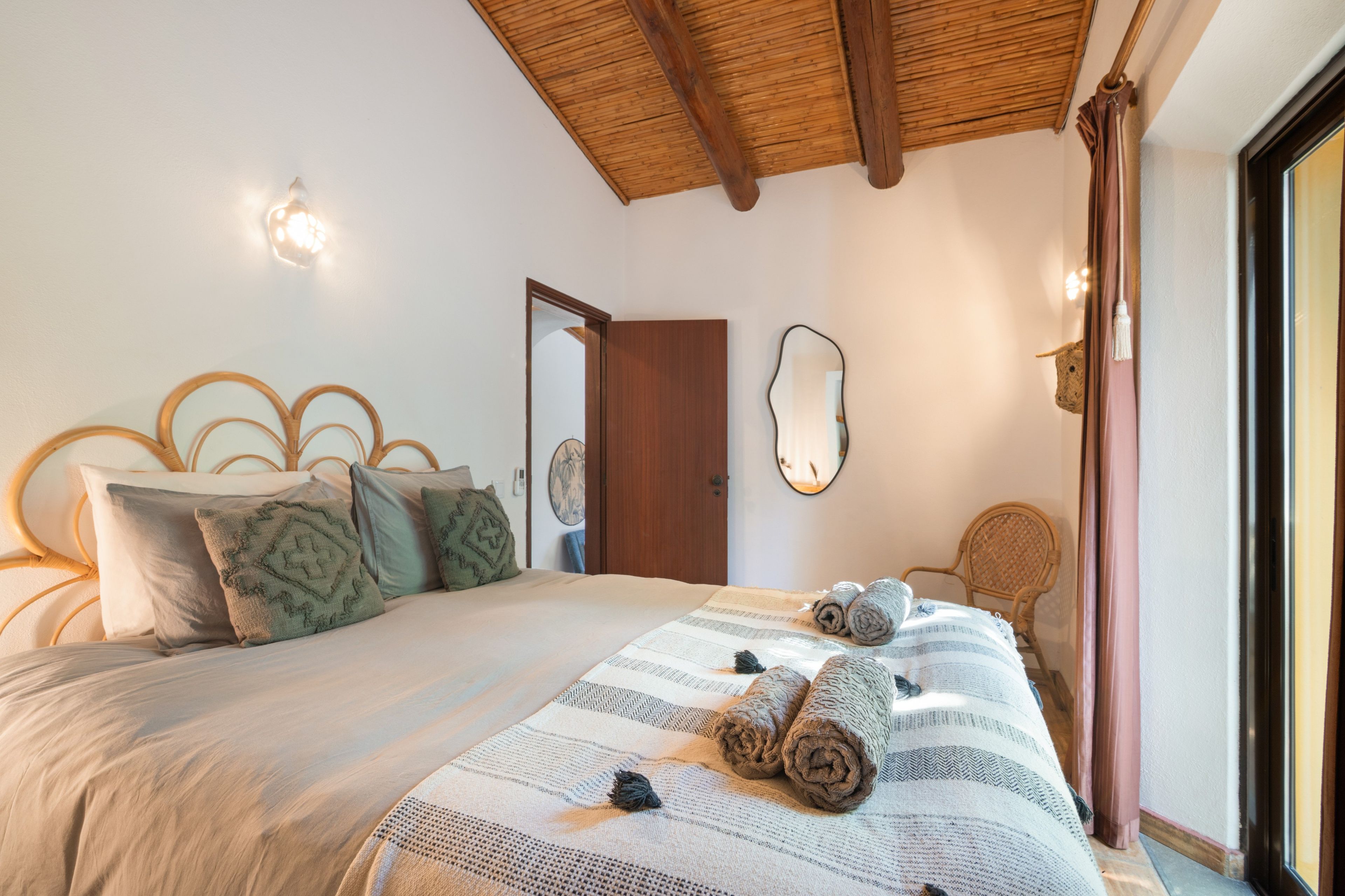 Ein Schlafzimmer mit einem Bett, einem Holz-Kopfteil, einem Spiegel und einer Tür.