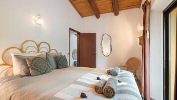 Un dormitorio con cama, cabecera de madera, espejo y puerta.