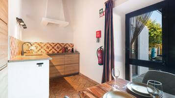 Een kleine keuken met een houten aanrecht, een koffieapparaat en een brandblusser aan de muur.