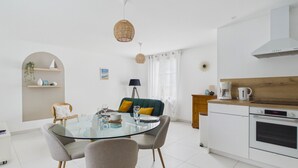 Una cocina moderna con armarios blancos, horno integrado y cafetera.
