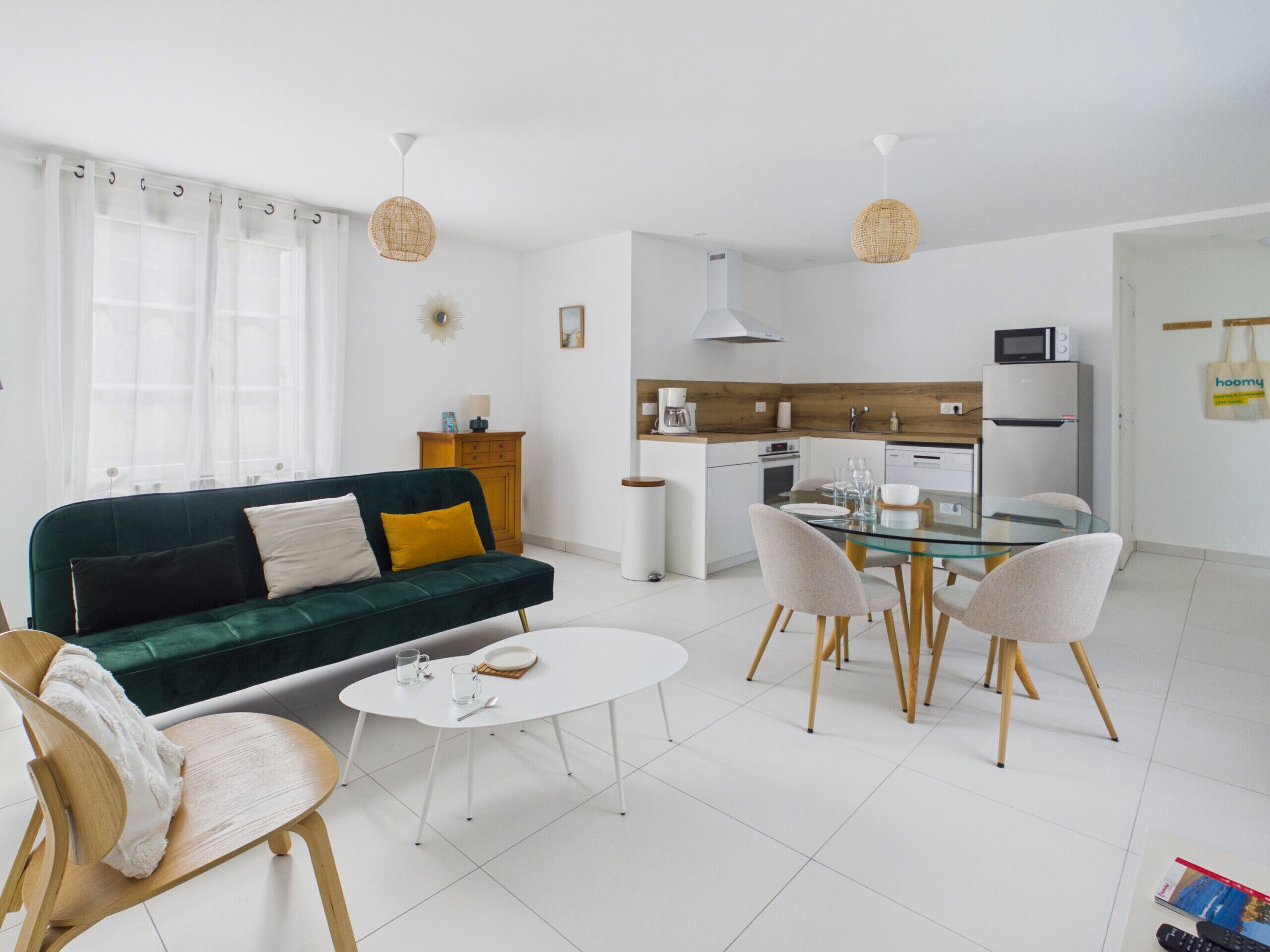 Ein modernes Wohnzimmer mit einem grünen Sofa, einem weißen Couchtisch und einem Esstisch aus Glas mit Stühlen.