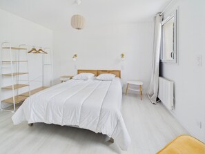 Et minimalistisk soveværelse med seng, sengeborde, et klædeskab og en radiator.