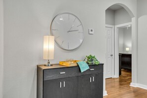 Un interior moderno con un reloj de pared grande, una lámpara, un adorno decorativo y una planta en maceta.