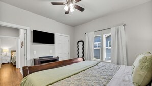 A bedroom with a bed, a ceiling fan, a television, a dresser, and a window with curtains. - 7th St Retreat-Tv's in Every Bedroom-Fully Fenced (Tulsa)