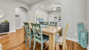 A dining area with a wooden table, chairs, and a ceiling fan. - 7th St Retreat-Tv's in Every Bedroom-Fully Fenced (Tulsa)