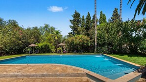 A rectangular swimming pool with a tiled edge, surrounded by a stone deck.