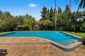 A rectangular swimming pool with a tiled edge, surrounded by a stone deck.
