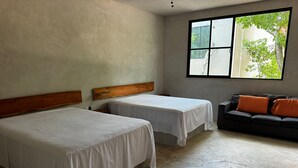 A room with two beds, a sofa, and a window with a view of greenery. - Hacienda Ticuch Valladolid (Valladolid)