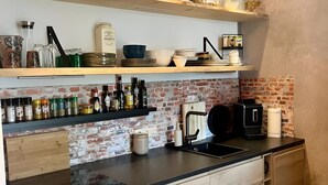 Een moderne keuken met houten kastjes, een vaatwasser en een backsplash van baksteen.