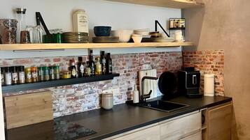 Een koffiezetapparaat/waterkoker, een koelkast, een oven, een kookplaat