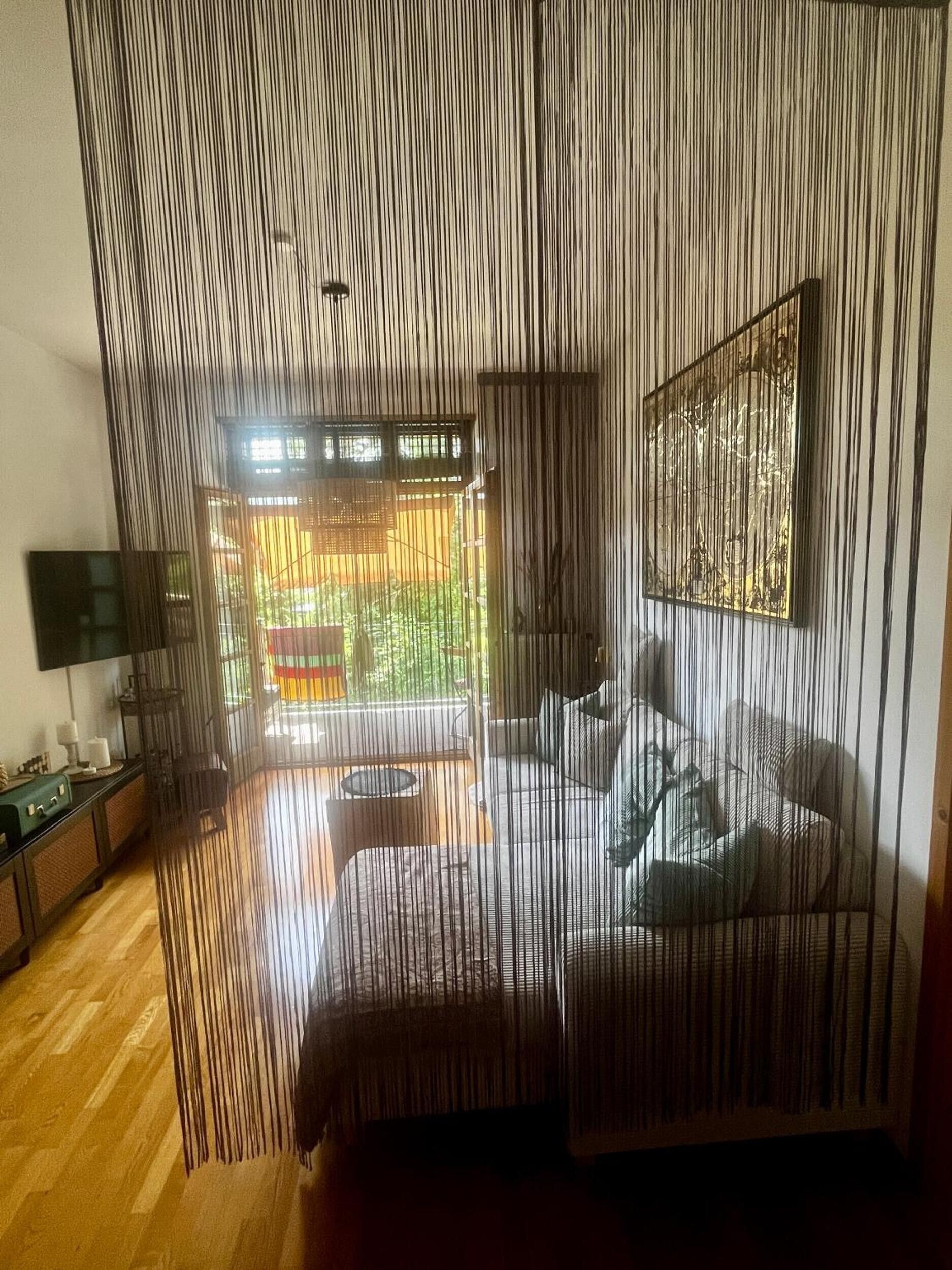 Ein Zimmer mit großem Fenster, einer Couch, einem Fernseher und Holzboden.