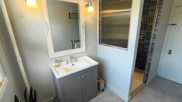 A bathroom with a white sink, a mirror with a decorative frame, and a shower area with a glass door.