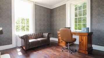 Una habitación con un sofá de cuero, un escritorio de madera y una silla.