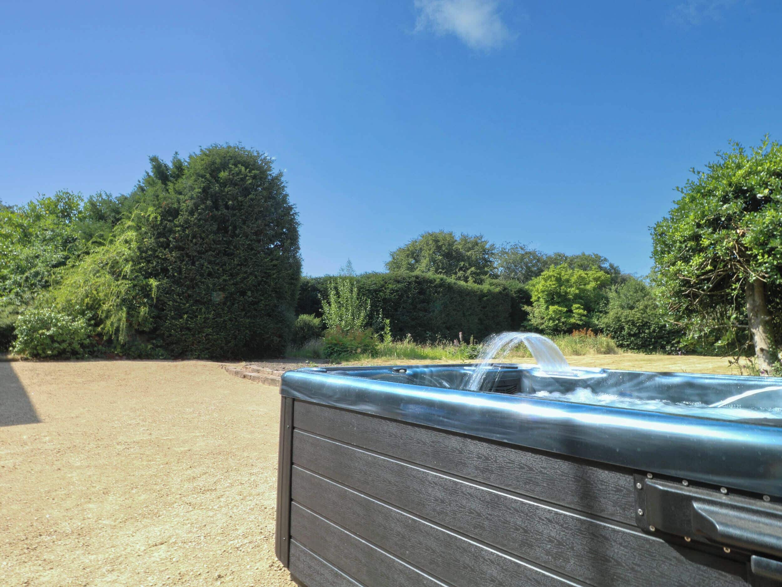 A hot tub in a garden with a clear sky.