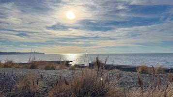 A beach with a rocky foreground and a calm sea under a partly cloudy sky.