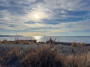 A beach with a rocky foreground and a calm sea under a partly cloudy sky. - Quiet Birch Bay Escape | Walk to Beach & Fun (Blaine)
