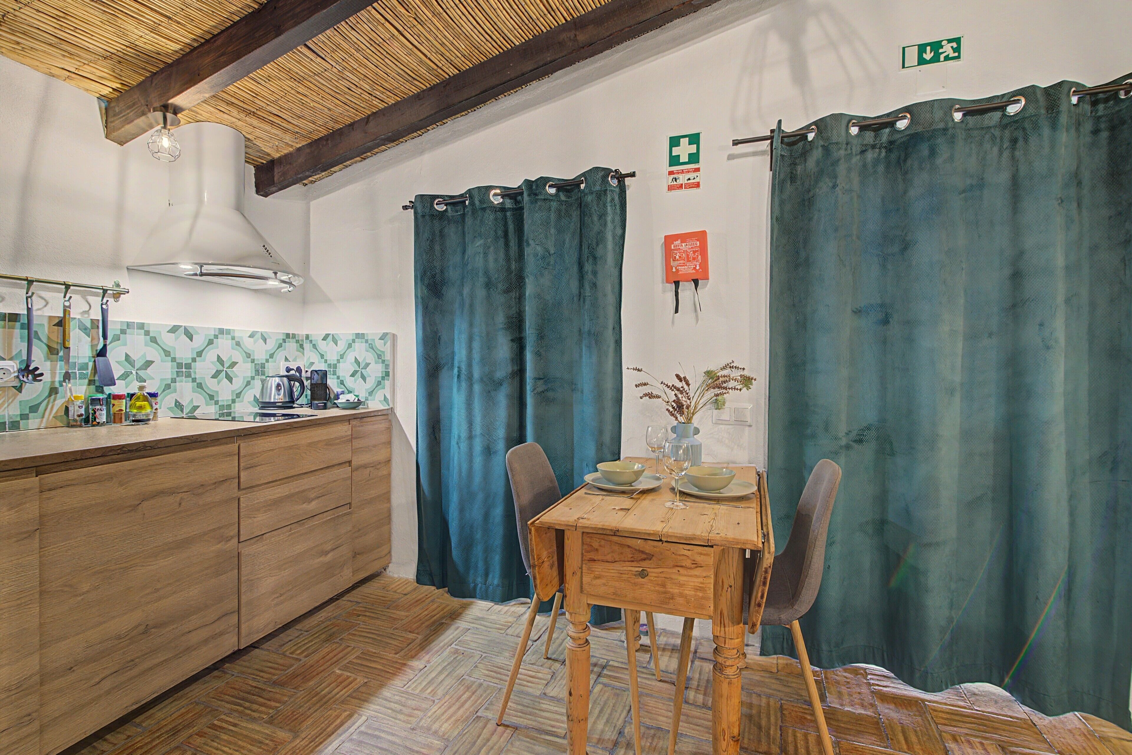 Una cocina con armarios de madera, estufa a gas y una lámpara colgante.
