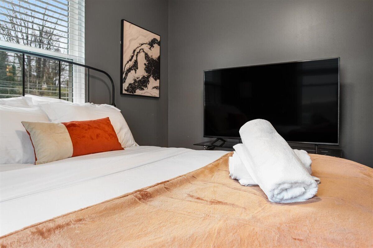 Een hotelkamer met een bed, een televisie en een raam met zonwering.