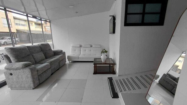A modern living room with a grey sofa, a white sofa, a small table with a plant, and a large window. - HOTEL SOFI CA BOUTIQUE (Bogotá)