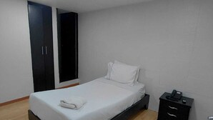 A bedroom with a bed, a wardrobe, a nightstand, and a door. - HOTEL SOFI CA BOUTIQUE (Bogotá)