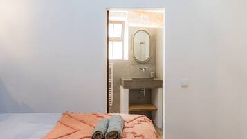 A bedroom with a bed, a bathroom visible through an open door, and a towel on the bed.
