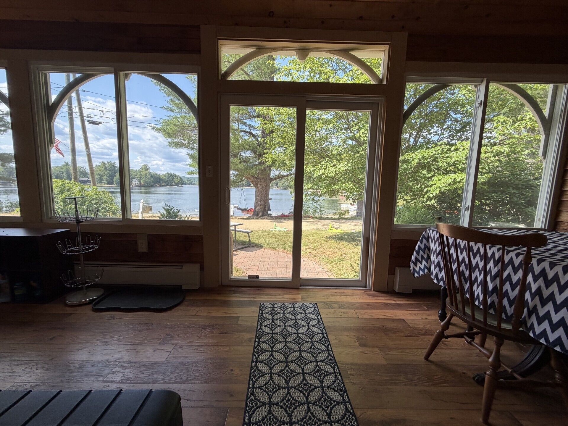 A room with a view of a lake, a bench, a table, and a chair.