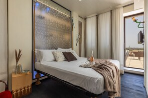 A hotel room with a bed, a bedside table, a TV, and a view of the outdoors. - Ultra-Lux Tower Villa: Dual Pools, Near Beaches (Gallipoli)