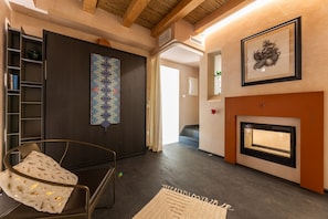 Ein modernes Wohnzimmer mit Kamin, einem gemusterten Wandteppich und einem Bücherregal.