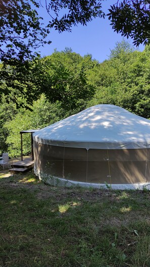 Une grande structure extérieure couverte, peut-être une tente ou un kiosque, dotée d’une armature métallique et d’un toit.