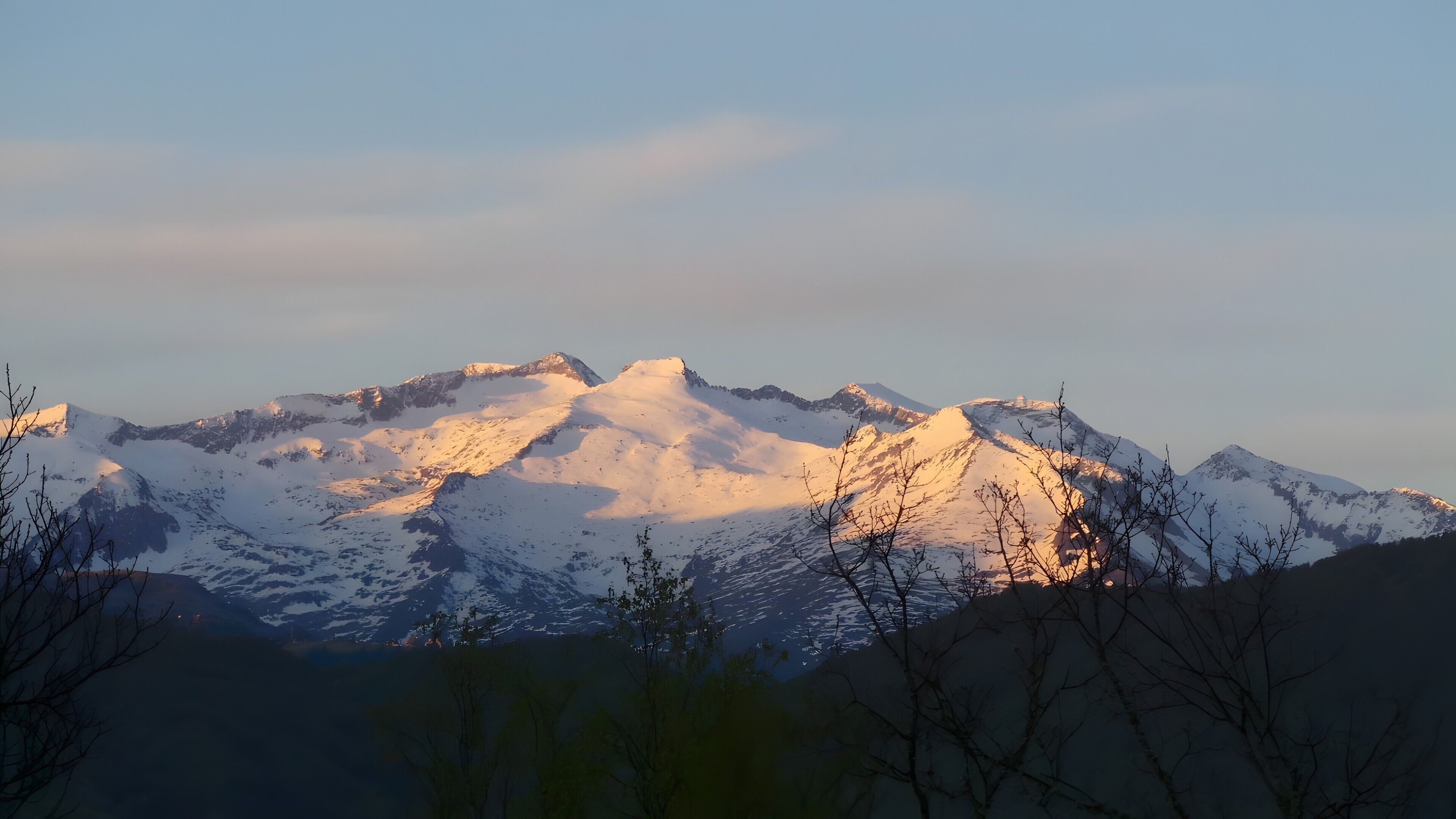 A mountain range with snow-covered peaks and a clear sky.