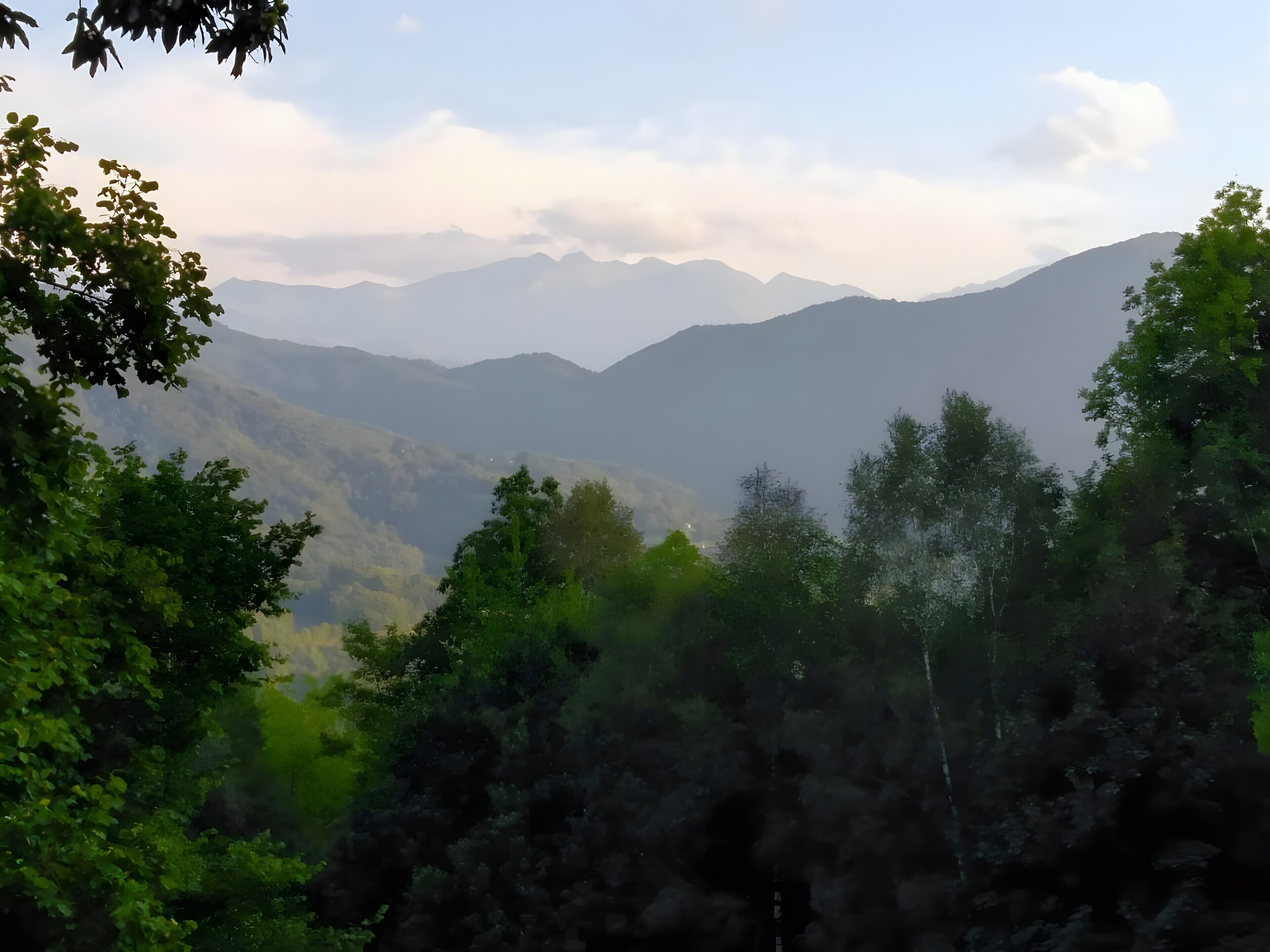 Eine gebirgige Landschaft mit dichten Wäldern und blauem Himmel.