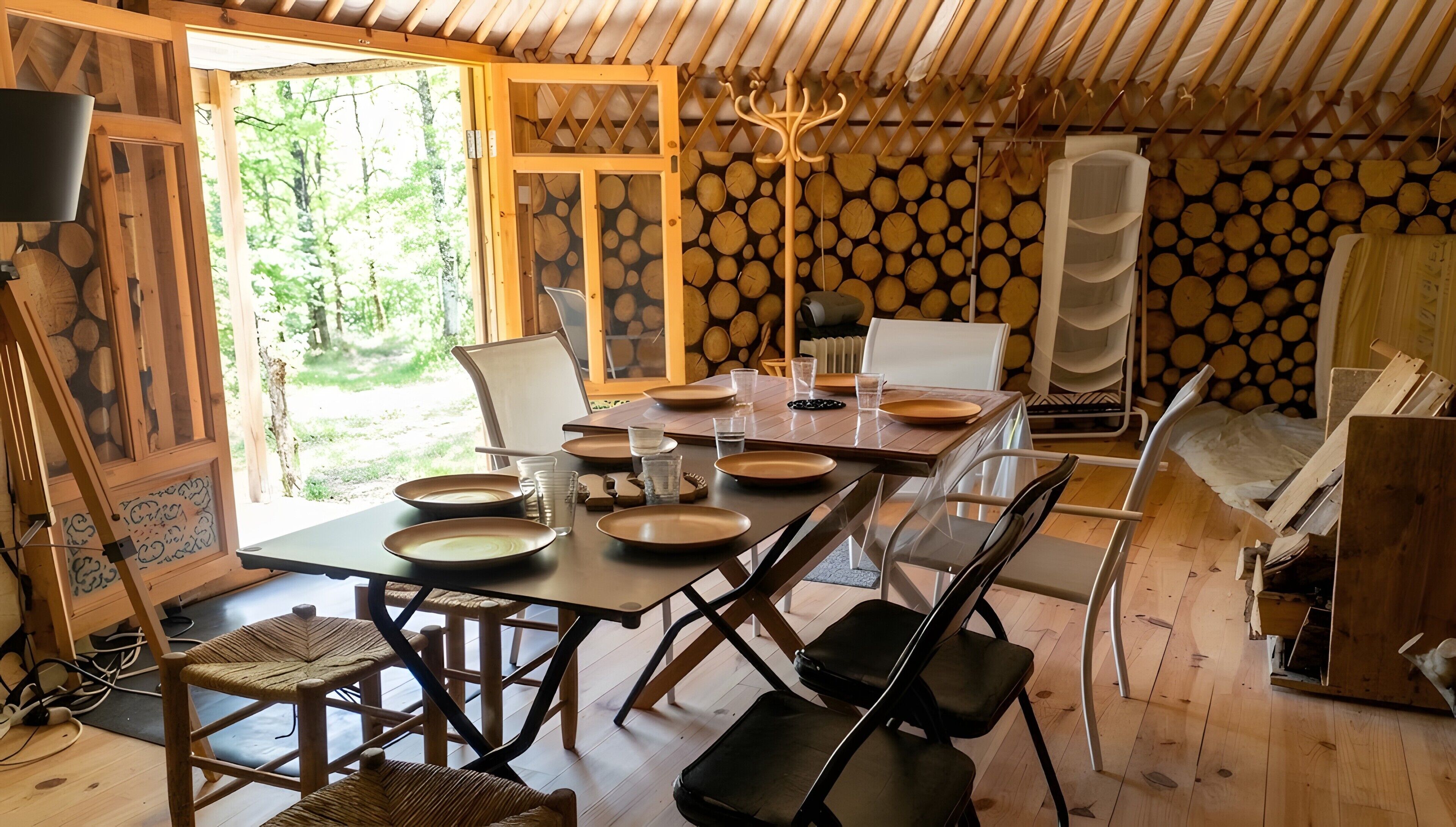 Comedor con una mesa dispuesta para cuatro personas, sillas alrededor y vistas al exterior.