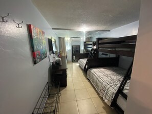 A dormitory room with bunk beds, a desk, a chair, a small cabinet, and a wall-mounted TV. - Casa Especial,5 spacious bedroom house with roof top terrace, 20 minutes from SJ (ToaBaja)
