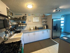 A modern kitchen with white cabinets, a gas stove, a microwave, and a refrigerator. - Casa Especial,5 spacious bedroom house with roof top terrace, 20 minutes from SJ (ToaBaja)
