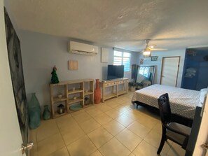Une chambre à coucher avec un lit, un bureau, une télévision et une fenêtre.