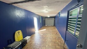 Un couloir aux murs bleus, doté d  ’un sol carrelé et d’une porte avec des stores.