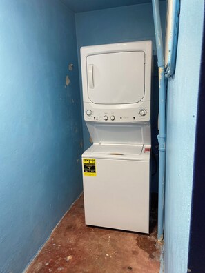 A laundry room with a white washer and dryer, a blue wall, and a brown floor. - Casa Especial,5 spacious bedroom house with roof top terrace, 20 minutes from SJ (ToaBaja)